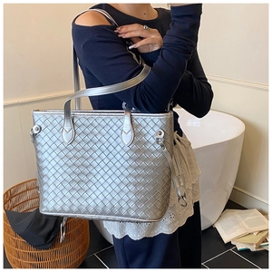 Detail of silver woven tote bag featuring wide metallic texture cross-weave and soft handles
