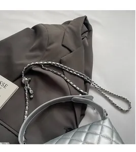 Close-up of silver quilted crossbody bag featuring metal chain strap and spherical buckle