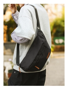 Détail d'un sac bandoulière noir avec sangle en nylon et étiquette en cuir brun