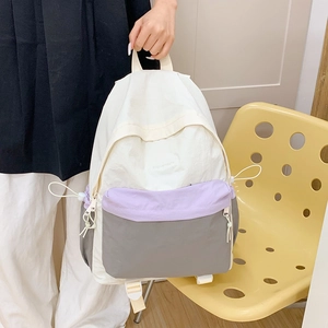 Detail of color-block nylon backpack featuring drawstring design and top carry handle