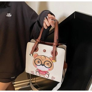 Detail of a white tote bag with a brown cartoon bear print and stylish wide strap