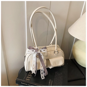 Detail of cream white boston bag with decorative lace bow and magnetic flap pockets