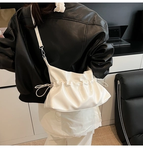 Détail du sac nuage blanc brillant avec design plissé et crochets métalliques
