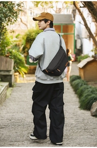 Modèle portant un sac de poitrine en nylon noir avec détails de fermeture en cuir