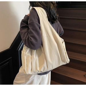 Vue latérale détaillée d'un sac cabas en toile beige avec poche latérale sur le mannequin