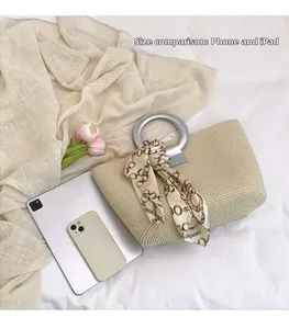 Detail view of woven tote bag size comparison with smartphone and tablet on white fabric
