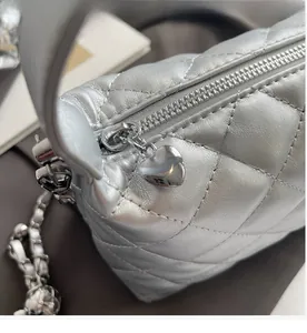 Close-up of quilted silver handbag featuring a smooth zipper and heart-shaped metal charm