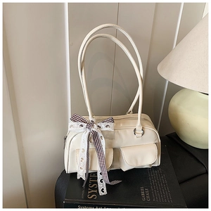 Detail of cream white shoulder bag with decorative bow on artistic book setting