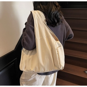 Détail d'un grand sac cabas en toile crème avec poche latérale sur un escalier épuré