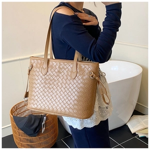 Detail of woven tan tote bag with intricate leather craftsmanship and long shoulder strap