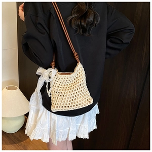 Détail du sac bandoulière tressé avec nœud en dentelle et breloque en perles