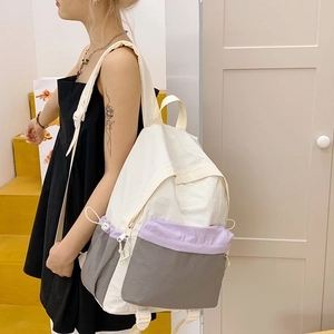 Side view of a color-block nylon backpack with purple accents on a model in sunlight
