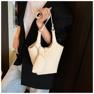 Beige pebble leather bucket bag shown on model featuring trendy dual pouch design