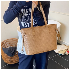 Detail of large brown woven tote bag showing fine texture and sleek shoulder straps