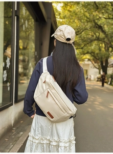 Détail d'un grand sac bandoulière beige avec texture en cuir fin et tirettes marron