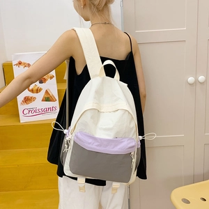 Detail of color-block nylon backpack featuring drawstring straps and multi-compartment design