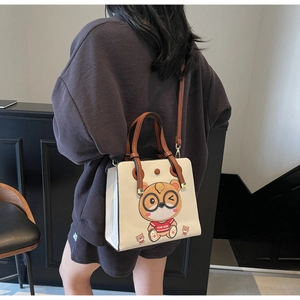 Close-up of white tote bag with brown straps and cute cartoon animal embroidery