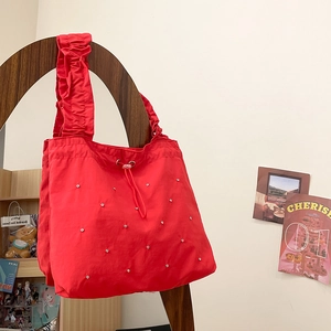 Detail of red nylon tote bag featuring ruffled handles and sparkling stud decorations