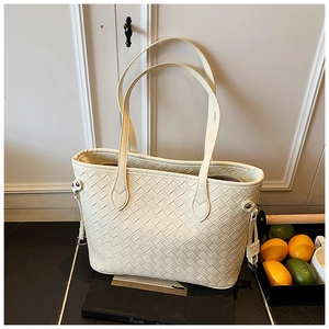 Close-up of cream white woven leather tote bag with dual handles and metal buckle detail