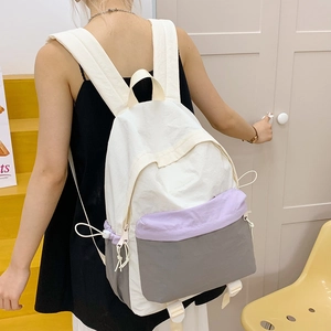 Detail of color-block nylon backpack with white drawstring and side pocket construction