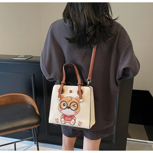 Detail of cream tote bag featuring a cute cartoon bear and brown shoulder strap