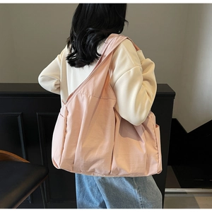 Grand sac fourre-tout rose pâle en nylon avec poches latérales porté par un mannequin