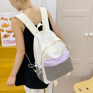 Detail of color-block nylon backpack featuring drawstring pockets and sleek patchwork design
