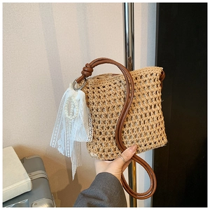 Détail du sac à bandoulière en paille tissée avec dentelle blanche et pendentif perle