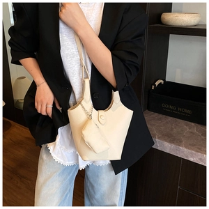 Detail of beige lychee texture bucket bag with matching coin purse on leather handle