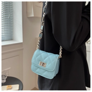 Detail of light blue quilted mini crossbody bag with silver moon chain strap on a model