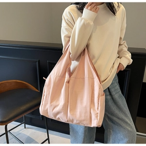Gros plan du sac cabas rose en toile avec poche latérale porté par un mannequin en salle