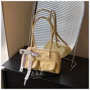 Detail of light yellow Boston bag featuring glossy finish and bow ribbon on handle