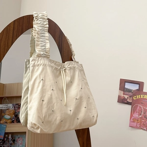 Close-up of beige nylon tote bag with ruffled shoulder strap and silver rhinestone details