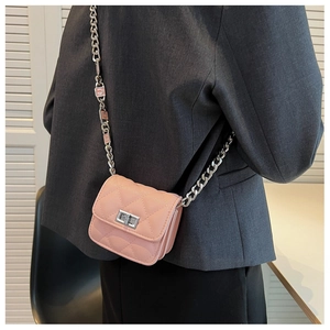 Detail of pink quilted mini chain bag with silver buckle worn over a grey suit