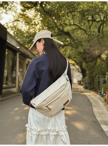 Détail du sac à bandoulière blanc cassé avec écusson en cuir et nylon résistant à l'eau