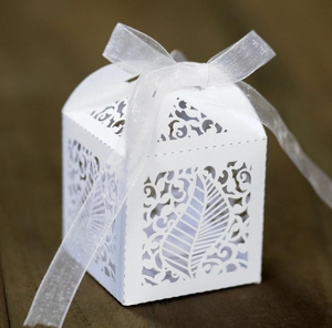 Detail of laser-cut leaf pattern on white favor box with elegant organza ribbon