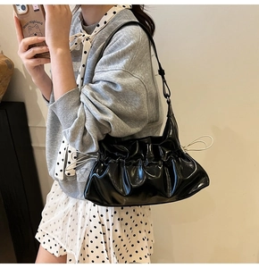 Détail d'un sac à bandoulière noir brillant avec design froncé et cordons de serrage