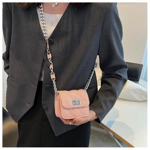 Detail of pink quilted mini crossbody bag with COCO lettered chain strap worn on grey blazer