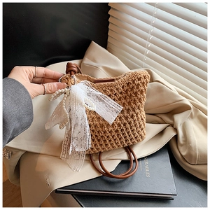 Vue détaillée du sac en paille avec nœud en dentelle blanche, perles et anses