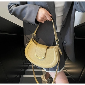 Detail of lemon yellow saddle bag with lychee texture and golden hardware clasp