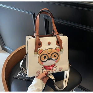 Detail of lychee pattern leather tote bag with cartoon bear and wide letter strap