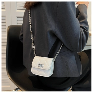 Close-up of a white quilted mini crossbody bag with silver lock and leather chain strap