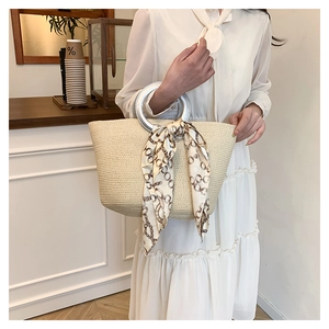 Detailed view of beige straw woven tote with silver ring handle and silk scarf decor