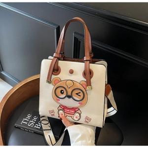 Detail of beige tote bag with cartoon bear embroidery and stylish woven crossbody strap
