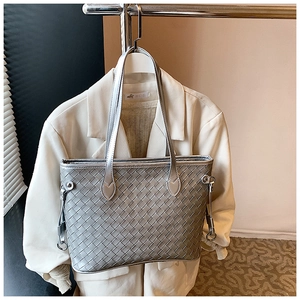 Close-up of silver woven tote bag with intricate leather texture and metallic hooks