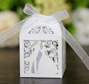 Detail of white laser-cut wedding favor box with groom bride silhouette and ribbon bow
