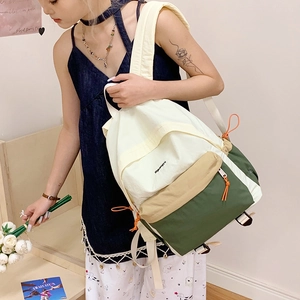 Detailed side view of nylon color-block backpack worn by a model in casual setting