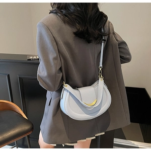 Detail of light blue hobo bag with litchi grain leather and gold metal crescent buckle