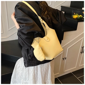 Close-up of light yellow pebble leather bucket bag with matching round coin pouch detail