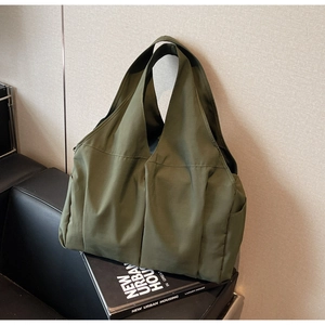 Détail d'un sac cabas plissé vert armée sur un canapé en cuir avec un livre urbain